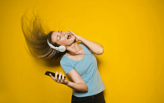 Mulher loira feliz com headphone e smarphone na mão